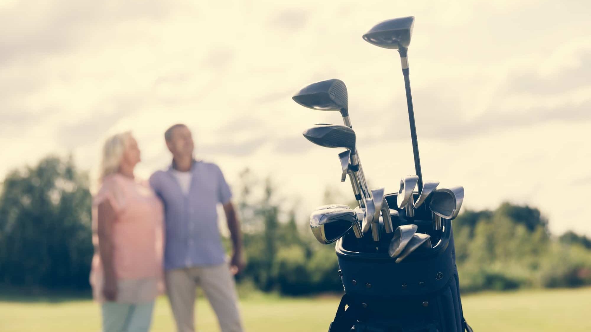 Golf bag standing on a grass field, people in the background